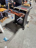 Full view of Rockwell table saw on rolling stand with cord and rails visible
