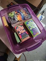 Open purple tote showing assortment of science-fiction anthology paperbacks