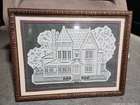 Full view of framed lace artwork showing house design and frame