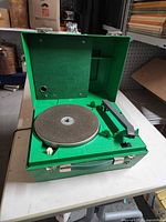Record player open showing platter, tonearm and green interior
