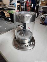 Full view of tea maker showing glass body, stainless control base, and handle