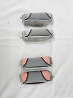 Four grey neoprene cylindrical hand weights, two with pink accents, two with purple accents