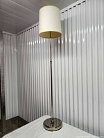 Full view of chrome floor lamp with cream drum shade