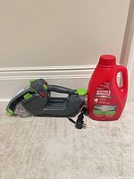 Spot cleaner, charger, and sealed solution bottle on carpet