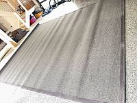 Full view of gray wool flat-weave rug laid out on floor showing overall size and bound edges