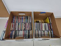 Two cardboard boxes filled with rows of CDs