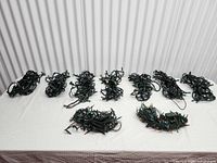 Nine coiled strands of Christmas string lights laid out on table