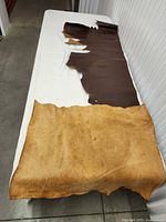 Tan and brown leather hides laid out on table