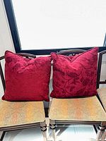 Front view showing both red jacquard pillows on chairs