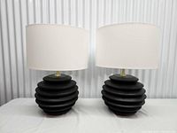 Front view of both lamps showing black tiered bases and white shades