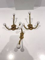 three brass hooks arranged on white surface