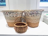 Two large straw and paper baskets with small rope basket in front