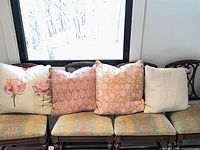 Four pillows on chairs: rose print, pink/gold damask, peach/gold jacquard, cream knit