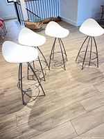 Four white STUA Onda bar stools on wood floor