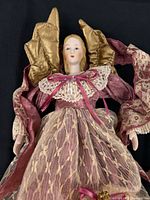 Close view of rose-gown angel showing molded face, lace bodice, gold wings