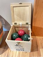 Open wooden case showing interior and several bocce balls