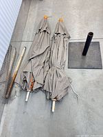 Two folded umbrellas, extension pole, and base shown together