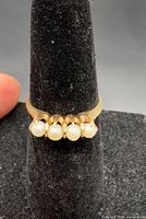 Front view showing four-pearl claw setting and gold band