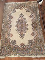 Full view of Persian Kerman rug showing entire design, central medallion, borders and fringe