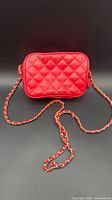 Front view of red quilted leather shoulder bag showing diamond pattern and full chain strap