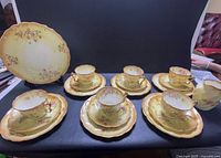 Full set laid out: 6 cup-saucer-plate trios, serving plate, creamer