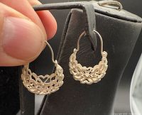 Pair of sterling silver filigree half-hoop earrings hanging on display stand