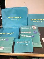 Six aqua travel pouches arranged showing size variation and branding