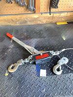 Overall view of hand cable puller showing handle, body, hooks, and snatch block