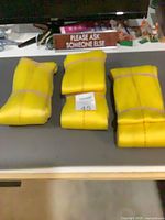 Three folded yellow heavy-duty straps on tabletop
