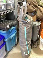Playpen folded inside gray carry bag with turquoise strap