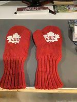 Pair of red knit mittens showing 2012 maple leaf patches