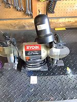 Front view of Ryobi bench grinder showing overall condition and accessories