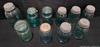 Ten blue-tinted jars with various lids displayed