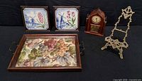 Group shot showing clock, two framed tiles, wooden tray, brass easel