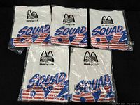 Top view of five sealed T-shirts showing front graphics