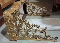 Pair of ornate gold-tone metal brackets with scrollwork patterns