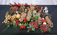 All items arranged on black surface showing pine cones, floral picks, baubles, metal ornaments and snowman