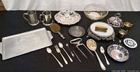 Group shot of all mixed silverplate and metal tableware pieces on table
