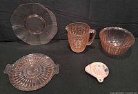Five items: four pink depression glass pieces and one ceramic juicer