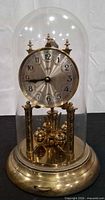 Front view of brass 400-day anniversary clock under glass dome