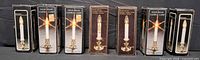 Front view of seven boxed solid brass electric candle lamps