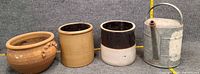Four items: terracotta planter, tan crock, two-tone crock, galvanized watering can