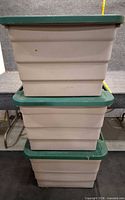 Three beige plastic totes stacked, green lids visible