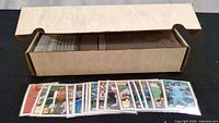 Long cardboard box half full of Topps baseball cards with several cards displayed in front