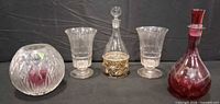 Group shot of all glass items: crystal rose bowl, two goblets, clear decanter with sleeve, red decanter