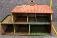 Front view of two-story tin dollhouse with removable roof and interior exposed
