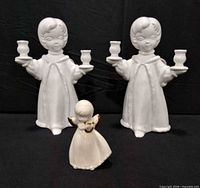 Front view of two white ceramic angel candle holders and matching small angel figurine