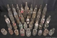 Front view of 45 clear glass bottles and jars arranged on black backdrop