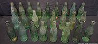Front view showing all 25 green Coca-Cola bottles standing