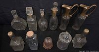 Group shot of eleven glass items including decanters, ewers, cloche and jar